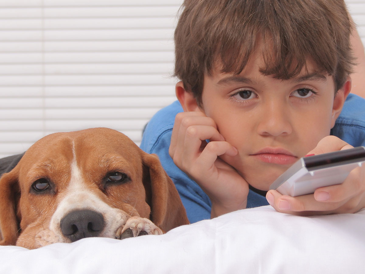 A bored boy and his dog watch television