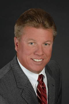 George C. Robinson III, President & CEO, South Jersey Yacht Sales, smiling and leaning toward the camera, wearing a grey suit, white shirt, and red tie.