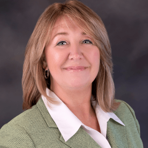 Elaine Dunner smiling in a light-colored business suit